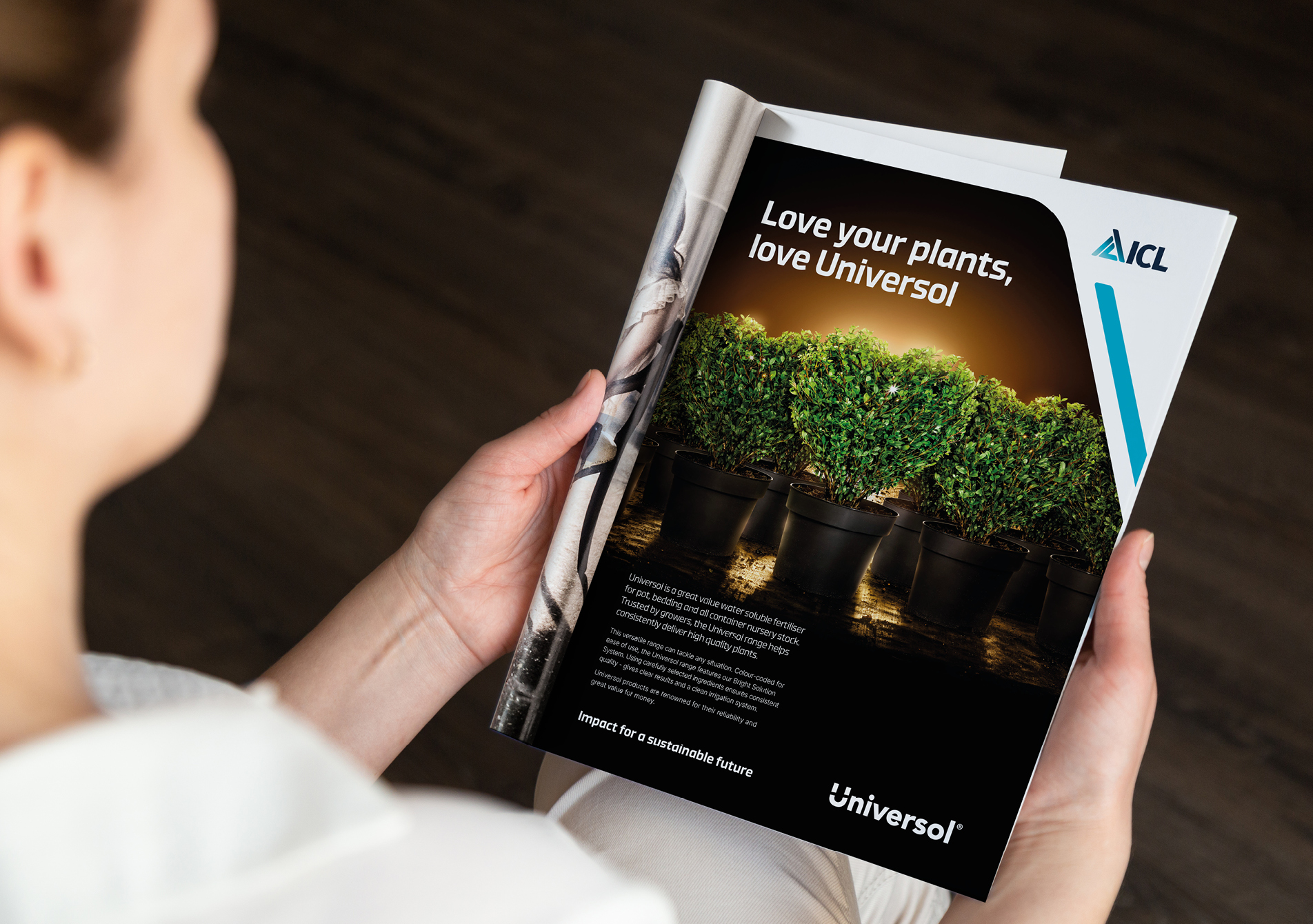 Man holding a magazine showing an advert design for ICL