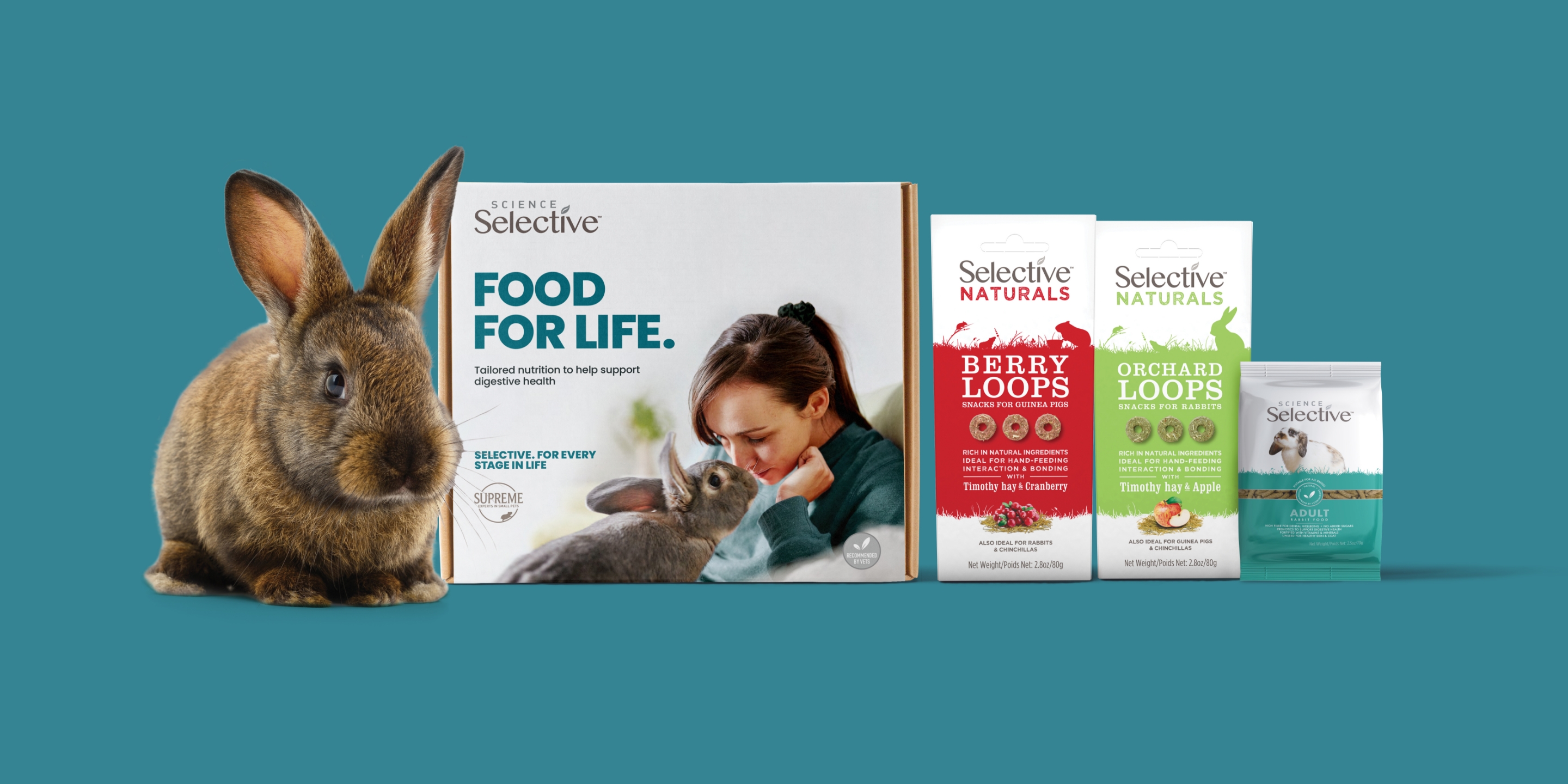 Rabbit beside boxes of Supreme Petfoods treats on a green background